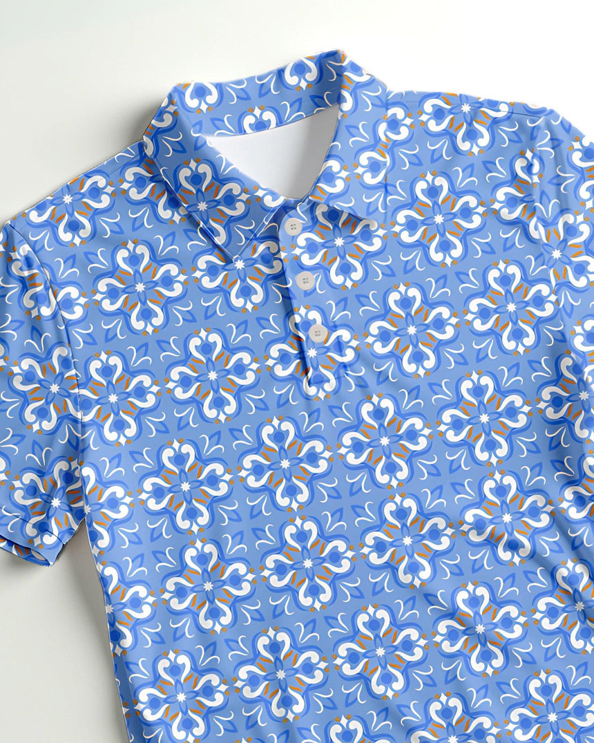 Close up of flat lay of light blue golf polo shirt with white and gold floral pattern