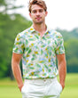 A man on a golf course wearing a colorful leaf print golf polo shirt