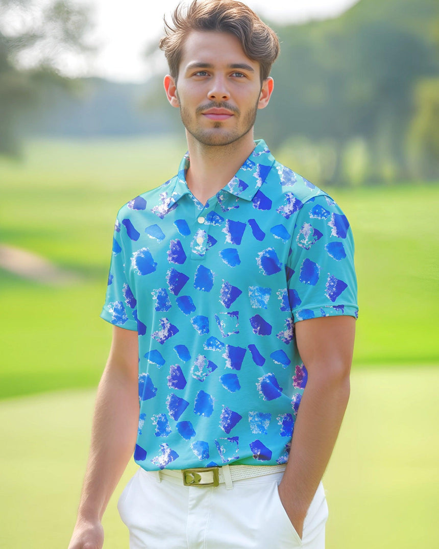 A man on golf course wearing a golf polo shirt with a dark blue confetti shape print on light blue