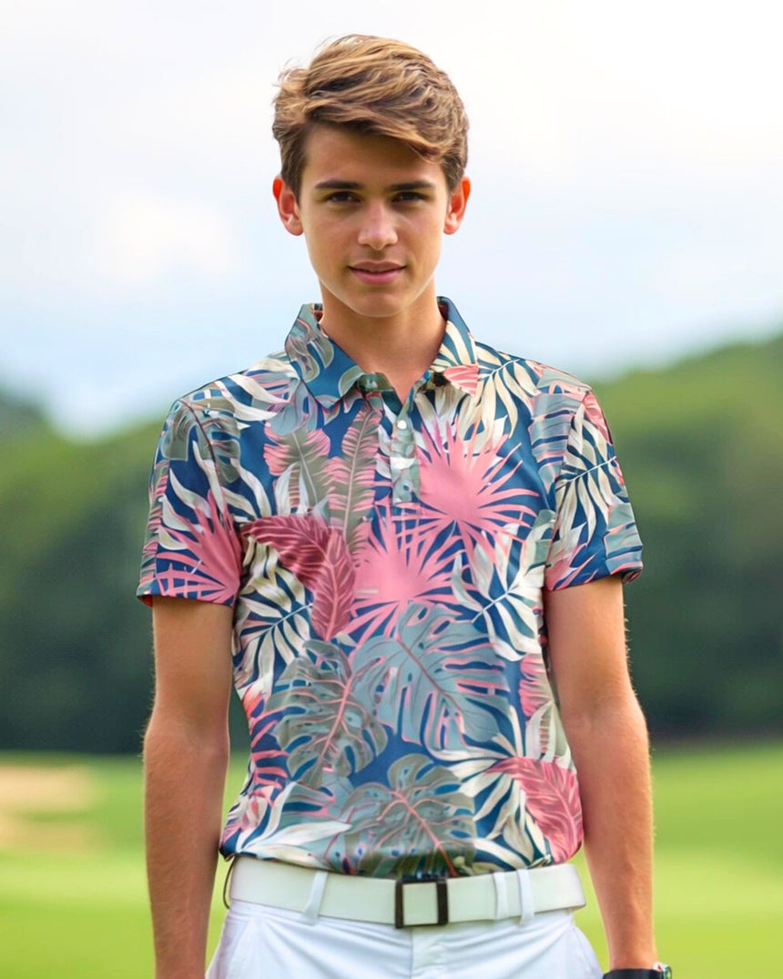 A young man wearing a golf polo with a tropical leaf pattern stands on a golf course.