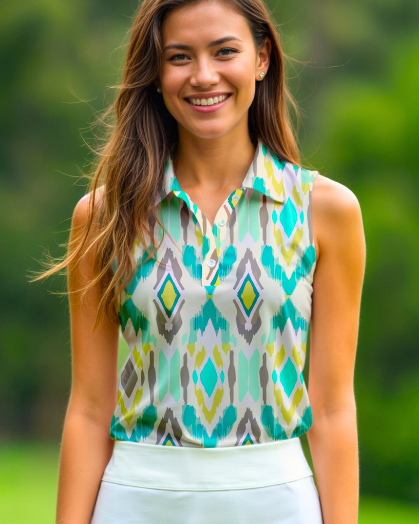 A smiling woman in a sleeveless golf polo with a geometric pattern of teal, yellow, and gray diamonds, paired with a white golf skirt.