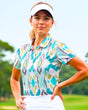 A woman wearing a white visor and a patterned golf polo with her hands on her hips.