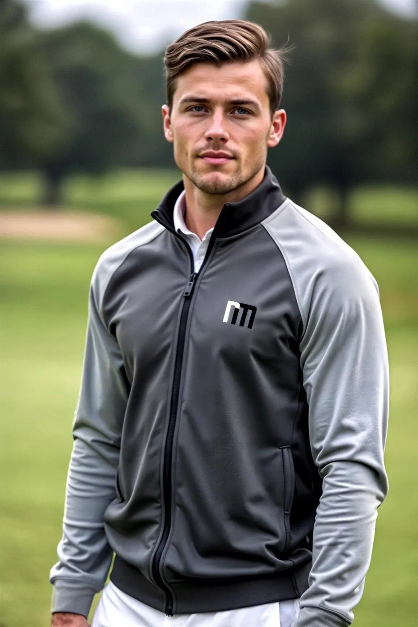 A man in a gray golf jacket with the brand logo on a golf course.