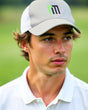 A man wearing a white golf polo and a gray hat with a logo.