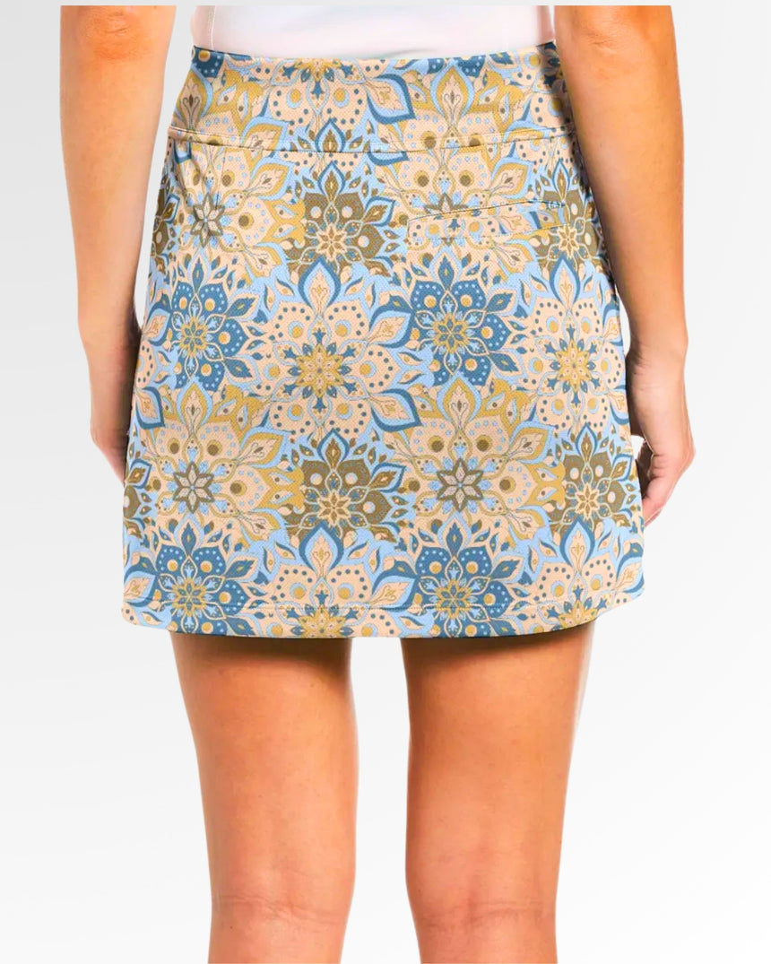 Close-up back view of a woman wearing a golf skort with a blue, tan, and gold floral pattern.