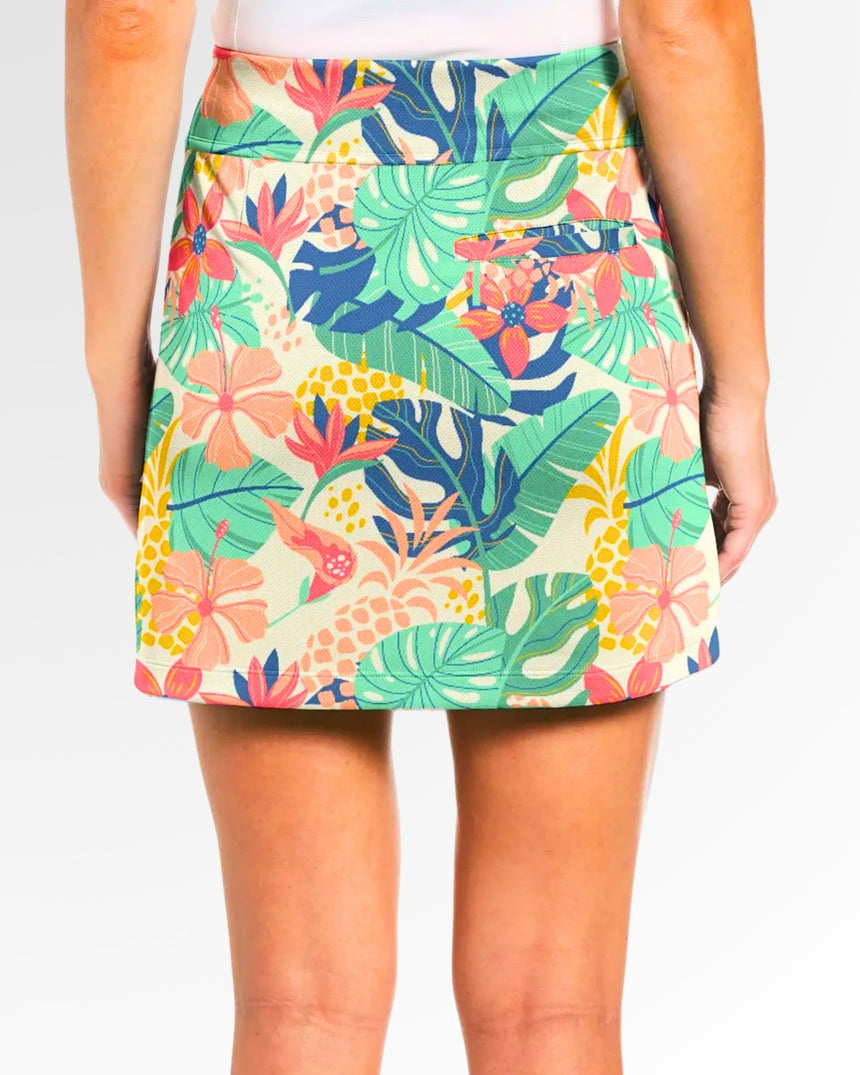 Close-up back view of a woman wearing a golf skort with a tropical floral and pineapple print.