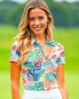 A smiling woman in a floral golf polo.