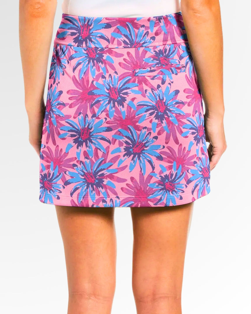 Back view of a woman wearing a pink golf skort with a blue and purple floral pattern.