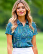 A woman with blonde hair smiles, wearing a patterned golf polo and white skirt.