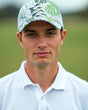 A close-up shot of a man wearing a white golf polo and a tropical print golf hat.