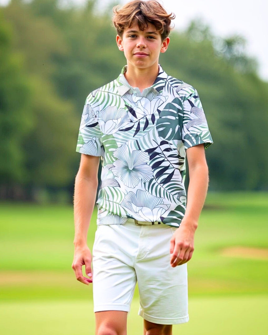 A young man in a floral golf polo and white shorts stands on a golf course.