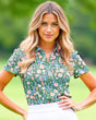 Woman wearing a floral patterned shirt with a blurred green background