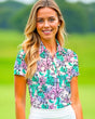 Woman wearing a colorful floral patterned golf shirt on a green outdoor background