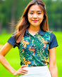 Woman wearing a colorful tropical leaf patterned shirt with a blurred green background
