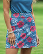 Woman on a golf course wearing a blue and pink tropical floral golf skort