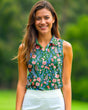 Woman wearing a floral sleeveless golf top with a blurred green background