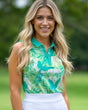 Woman wearing a green and white patterned sleeveless top with a blurred green background