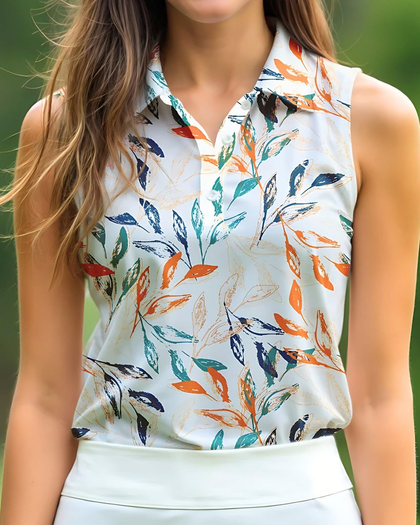 Woman wearing a sleeveless golf polo with colorful leaf pattern against a blurred green background
