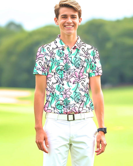 Teenager wearing a colorful floral shirt and white pants standing outdoors with greenery in the background