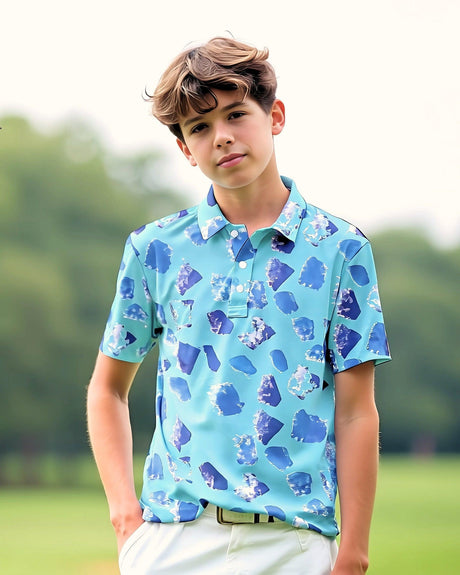 Young boy wearing a blue patterned polo shirt standing outdoors on a golf course