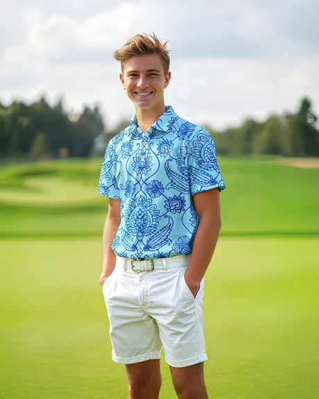 Young boy wearing a blue patterned polo shirt and white shorts on a golf course