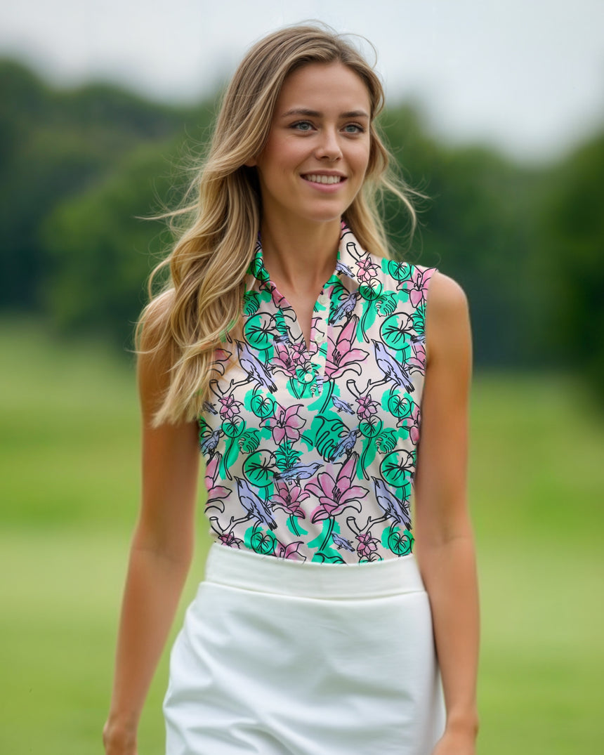 A blonde woman smiles while wearing a sleeveless golf polo with a floral and bird pattern and a white golf skirt.