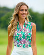 A woman smiles while wearing a sleeveless golf polo with a bird and flower pattern.