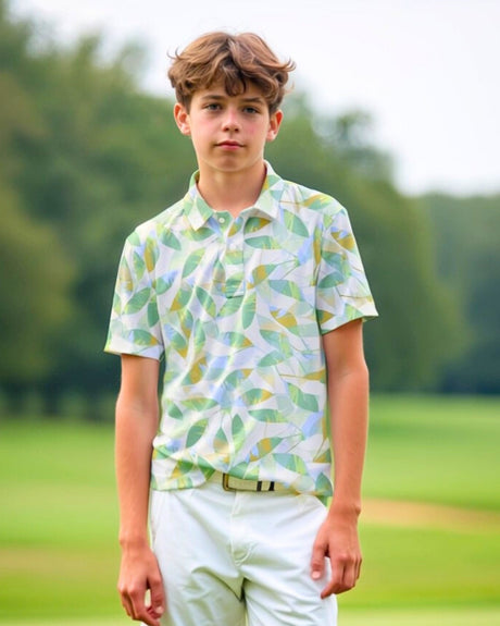 A young man stands on a golf course wearing a patterned golf polo and white pants.