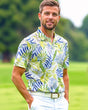 A man smiles wearing a golf polo with a tropical leaf pattern.