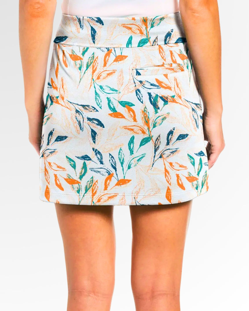 Close-up back view of a woman wearing a golf skort with a white background and a leaf pattern in shades of orange, green, and blue.