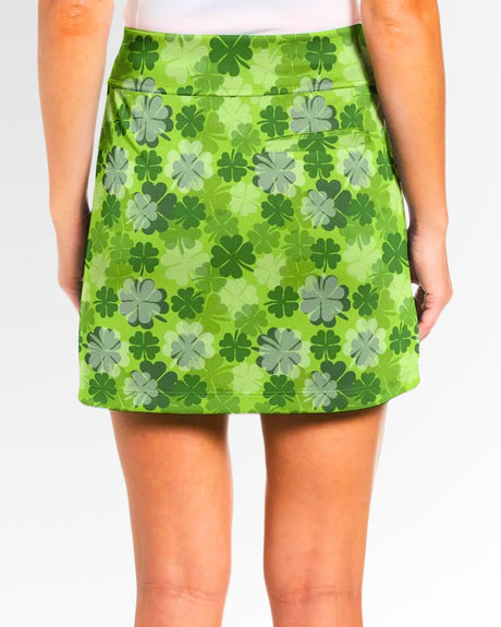 Close-up of a woman wearing a green golf skort with a clover pattern.
