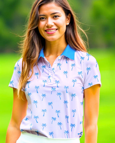 A woman smiles wearing a golf polo with a palm tree pattern.