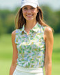 Woman wearing a sleeveless patterned top and white cap on a golf course