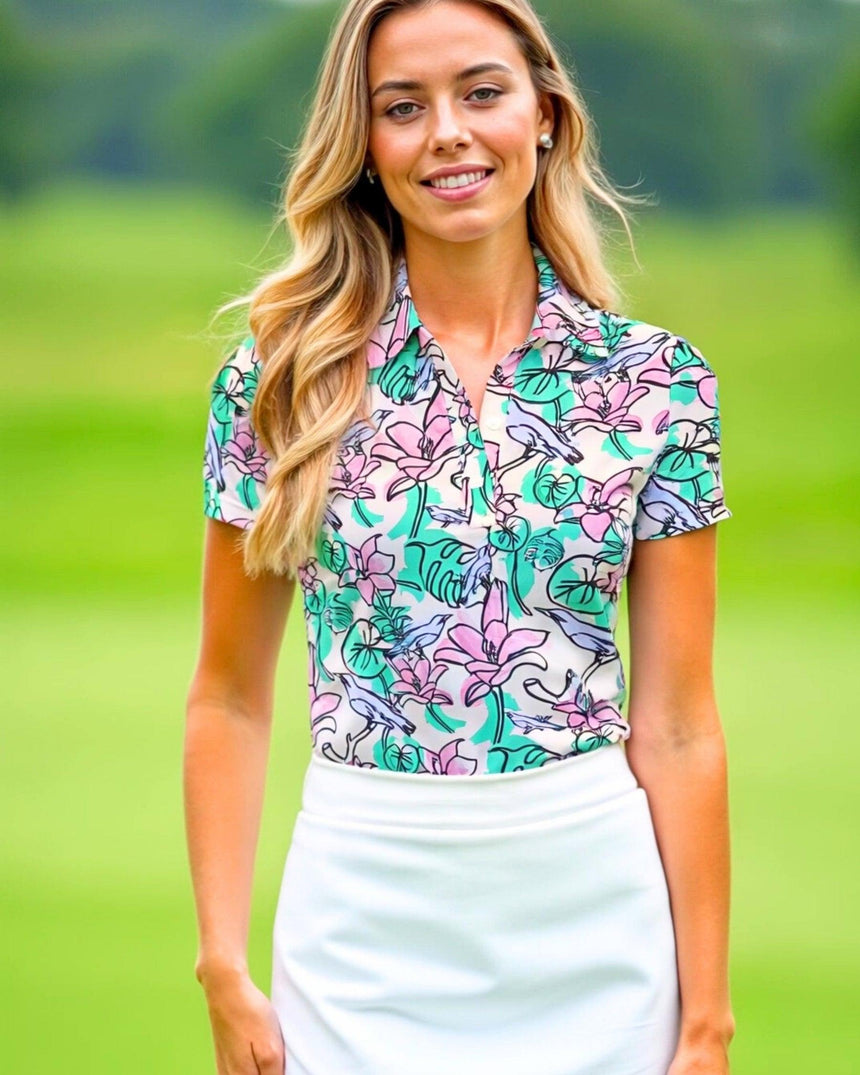 Woman wearing a colorful floral polo shirt on a green outdoor background