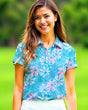 Woman wearing a blue floral golf shirt on a green outdoor background