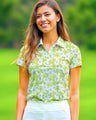 Woman wearing a green floral polo shirt standing on a golf course
