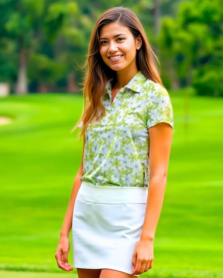Woman in a green and white floral polo shirt and white skirt standing on a golf course.