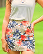 Woman wearing a floral golf skirt with a blurred green background