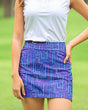 Woman wearing a white top and a blue patterned skirt on a green outdoor background