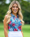 Woman wearing a colorful floral sleeveless golf polo top with a blurred green background