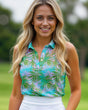 Woman wearing a colorful patterned sleeveless golf top with a blurred green outdoor background