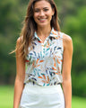 Woman wearing a sleeveless floral golf shirt and white pants outdoors