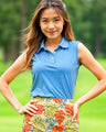 Woman wearing a blue sleeveless top and colorful floral skirt outdoors