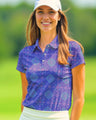 Woman wearing a purple patterned polo shirt and white cap on a golf course