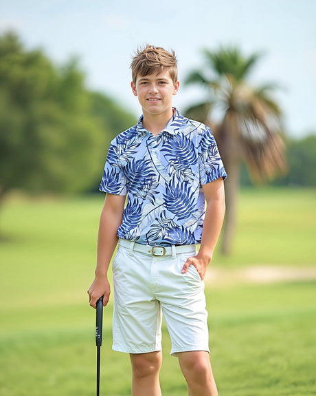Teenage boy in a blue and white tropical print polo shirt and white shorts standing on a golf course.