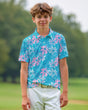 Young boy wearing a blue and pink floral polo shirt on a golf course